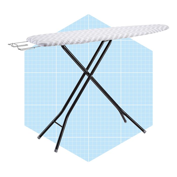 An ironing board with a gray chevron cover stands upright, featuring a side bracket for iron placement against a light blue grid background.
