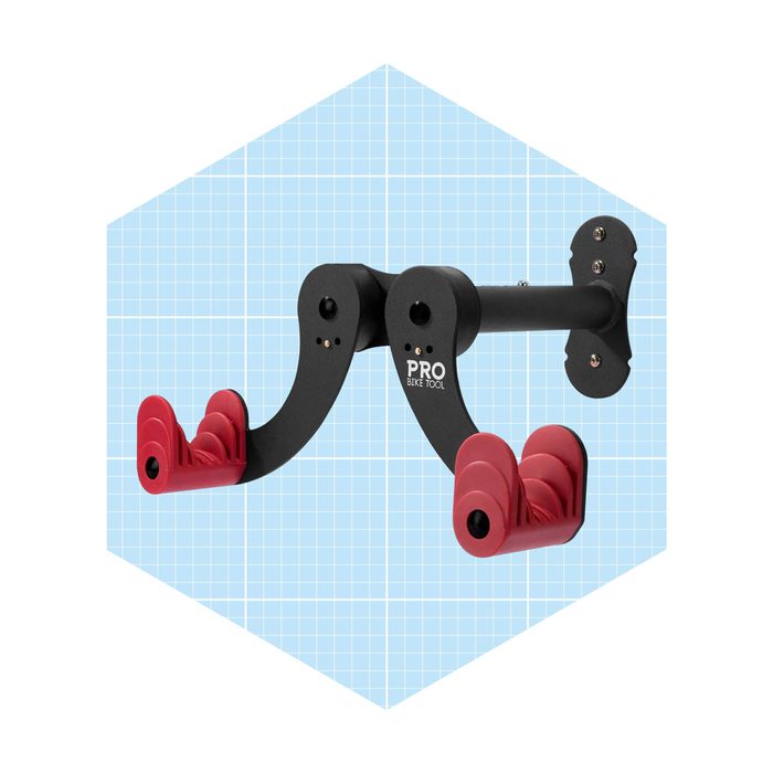 A bike storage hook securely holds bicycles in place. It is mounted on a wall against a light blue grid background, designed for efficient space use.