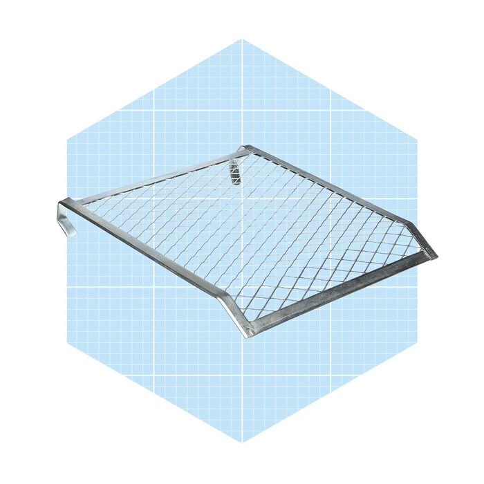 A metallic wire shelf is positioned at an angle, designed for storage or display, set against a blue grid background.