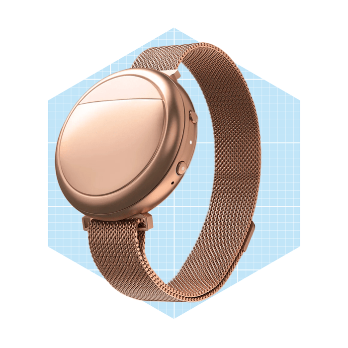 A rose gold smartwatch rests on a wire mesh band, showcasing a smooth round face against a light blue geometric background.