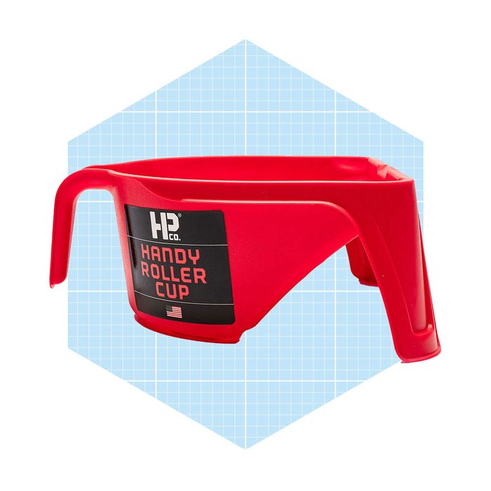 A red plastic cup with a handle is positioned against a light blue grid background, designed to facilitate easy paint application.