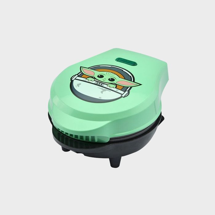 A green cooking appliance features a cartoon graphic of a character with large ears, designed for making waffles or similar foods.