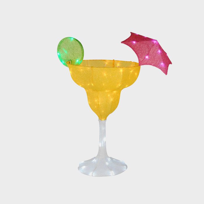 A bright yellow margarita glass with a green lime slice and a pink umbrella, illuminated with lights, stands on a clear base against a neutral background.