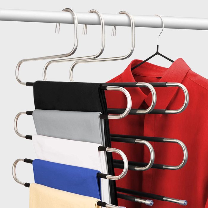 A series of hangers hold neatly folded shirts in various colors, while a red shirt hangs above on a single hook, all suspended from a rod.