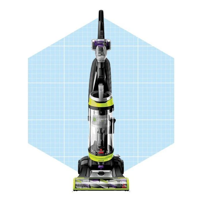 A vacuum cleaner stands upright, ready for use, within a light blue grid-patterned background, suggesting a clean, organized environment.
