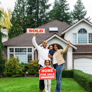 A family celebrates in front of a house, holding a 