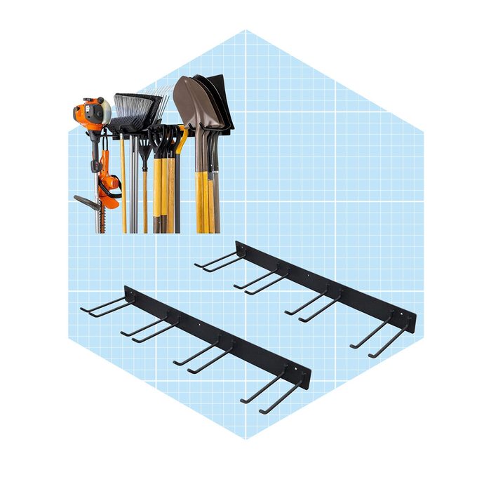 Gardening tools rest vertically on a wall-mounted rack beside hooks, designed for efficient storage. The background features a grid pattern in light blue.