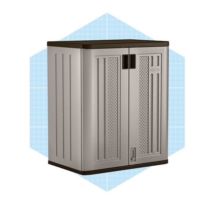 A gray storage cabinet stands upright, featuring double doors and ventilation patterns, set against a light blue geometric background.