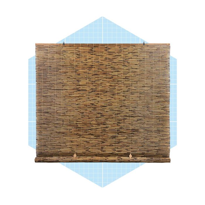 A bamboo blind hangs flat against a light blue grid background, providing a natural texture and style that filters light while maintaining privacy.