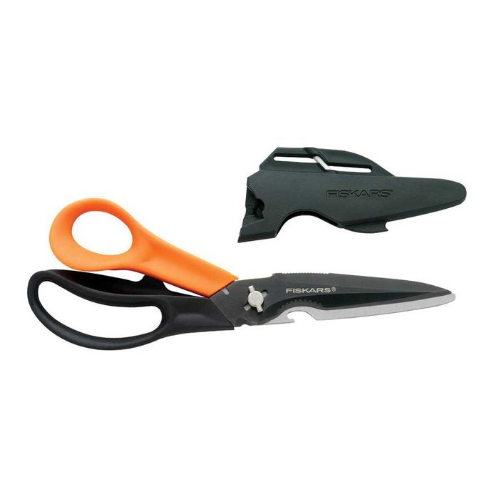 A pair of scissors with an orange and black handle sits next to a protective sheath, both designed for cutting and safety.