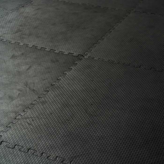 Black interlocking mats cover the floor, providing a textured surface that is well-suited for exercise or activities in a gym or play area.