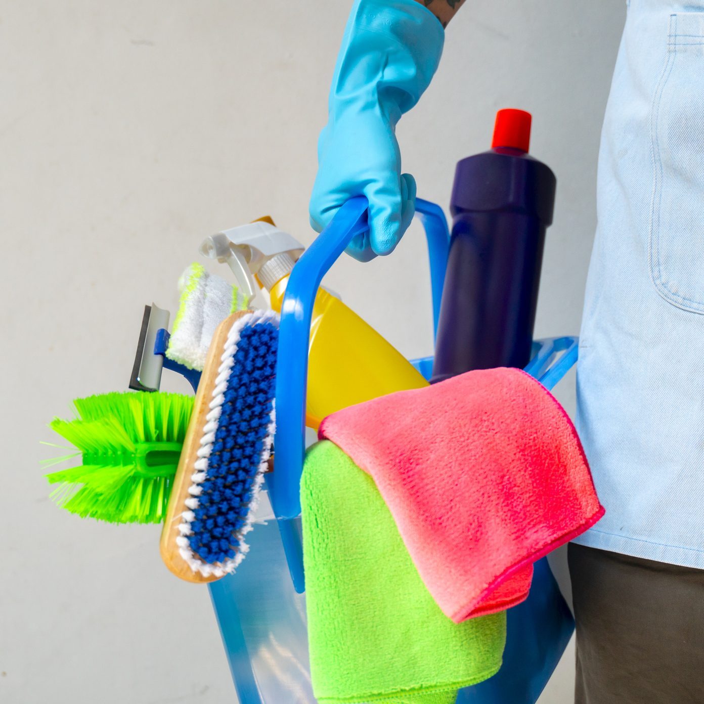 Man holding mop and plastic bucket with brushes, gloves and detergents in the kitchen