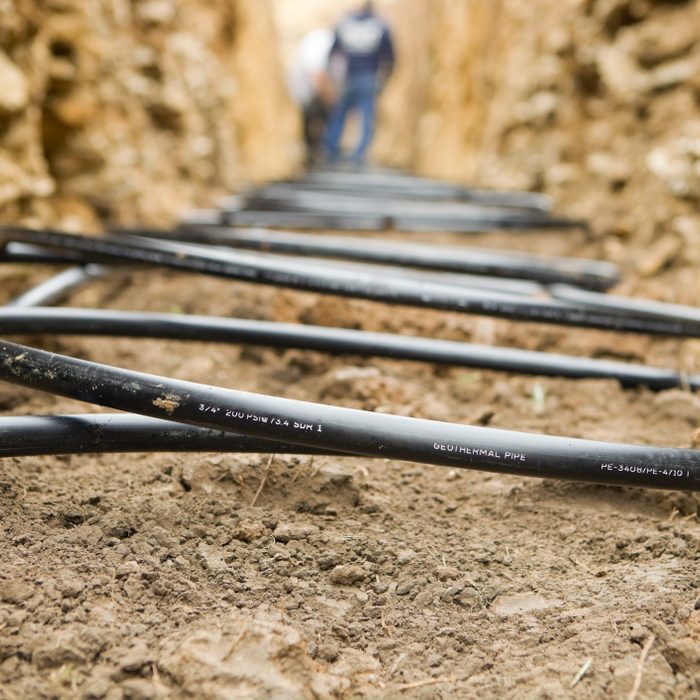 Workers Laying Geothermal Coils In An Underground Trench