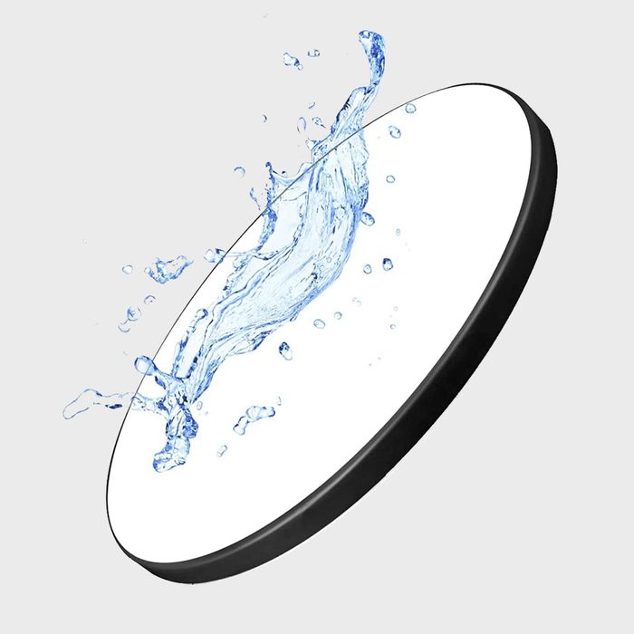 A round object, splashed with water, creates dynamic fluid shapes against a white background, emphasizing motion and freshness.