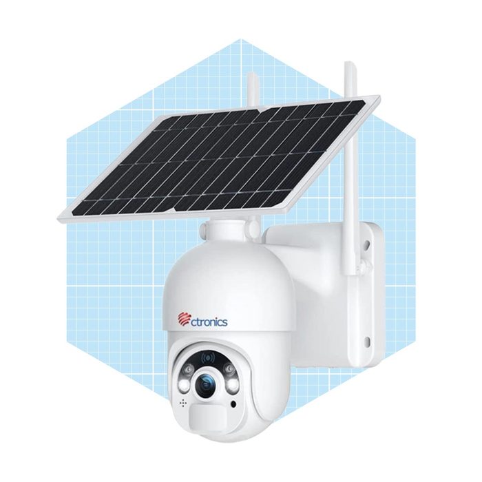 A solar-powered security camera is mounted on a wall, capturing footage in an outdoor setting. It features a sleek, white design with attached solar panels.