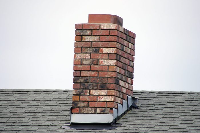 A brick small chimney on a the roof of home