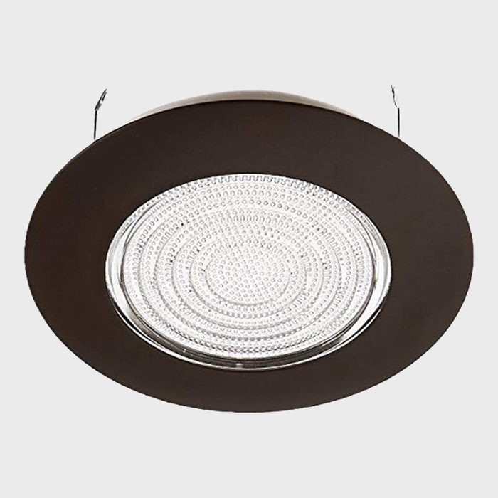 A round ceiling light fixture illuminates a space, featuring a patterned diffuser surrounded by a dark, circular frame, mounted from the ceiling.