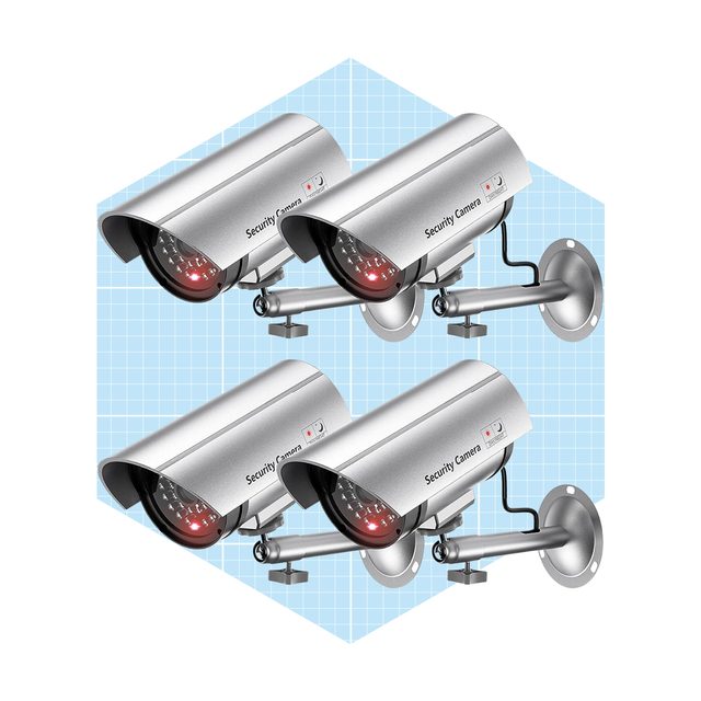 Four silver security cameras are mounted on walls, actively monitoring their surroundings, set against a light blue grid background.
