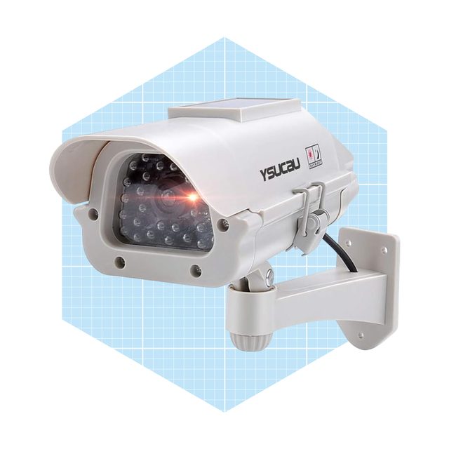 A security camera mounted on a wall, emitting a light, positioned within a blue-checkered background, designed for surveillance purposes.