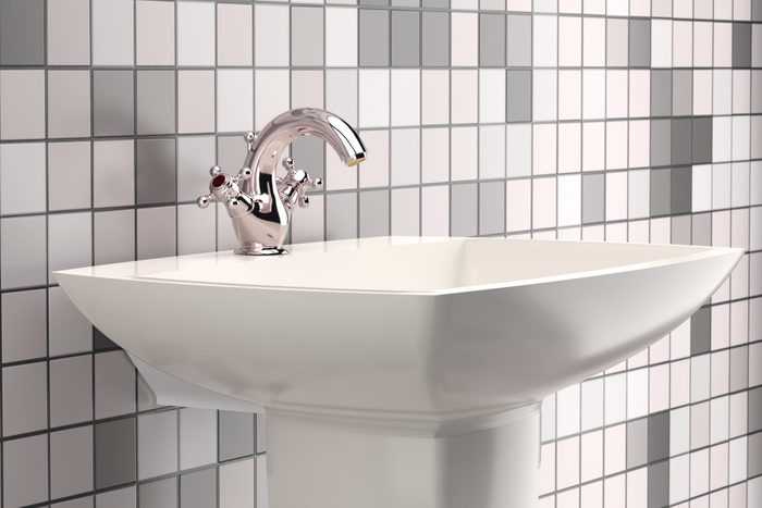 Close Up Of Faucet On Bathroom Sink Against Wall