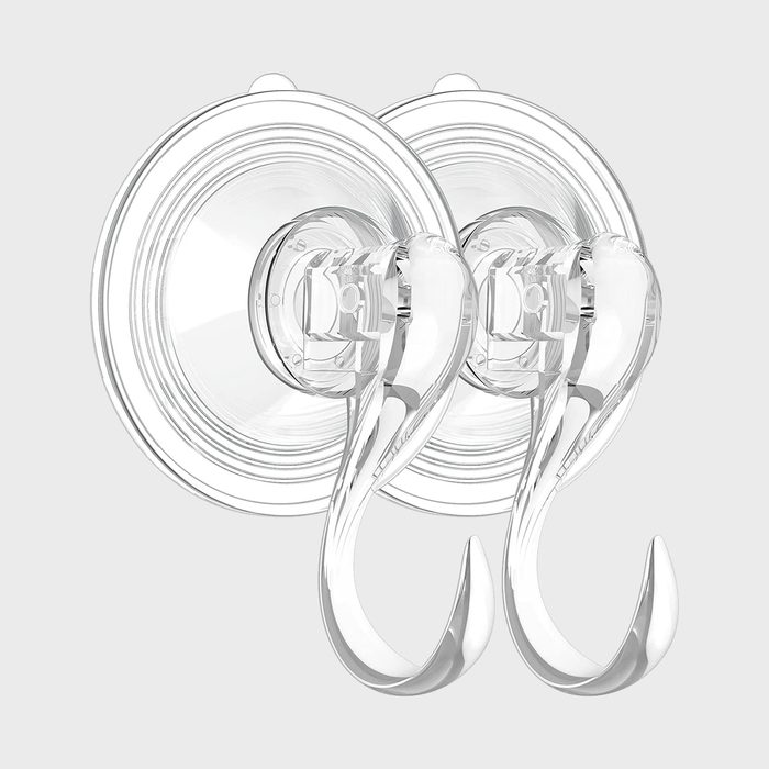 Two transparent suction cup hooks are mounted on a flat, light-colored surface, designed to hold items without causing damage.