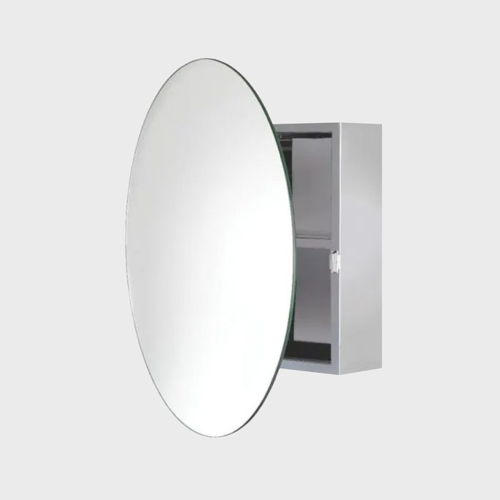 A circular mirror is mounted on a wall, with a cabinet behind it. The mirror reflects light, creating a bright and open appearance.