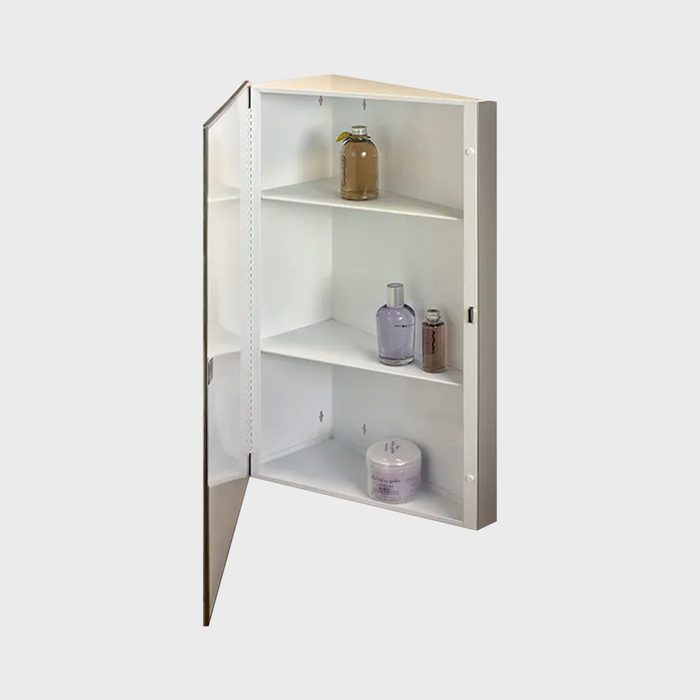 A white corner cabinet stands open, displaying three shelves holding various bottles and a container, set against a neutral background.