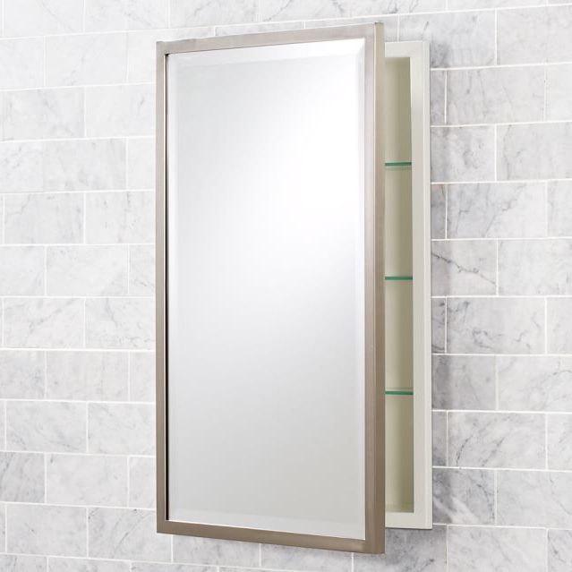 A rectangular mirror is mounted on a wall, opening to reveal shelves inside. The wall features light-colored, textured tiles.