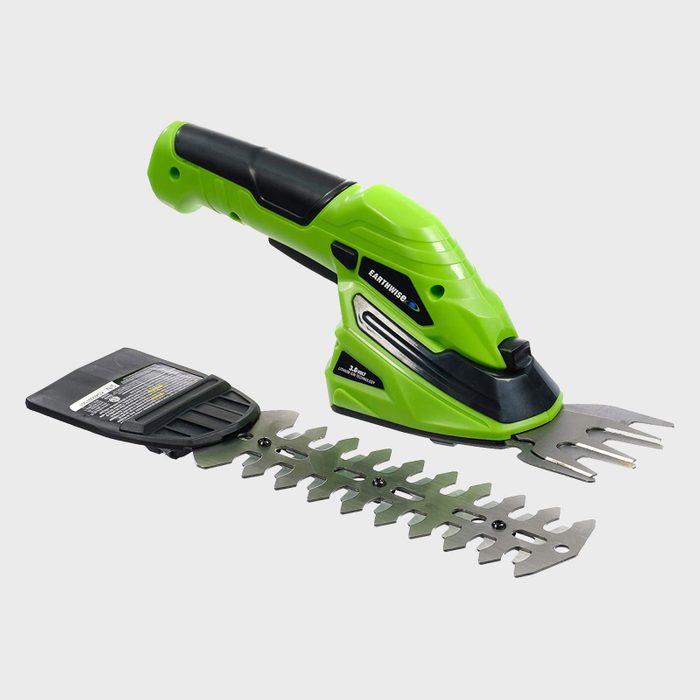 A green hand-held garden tool sits with interchangeable metal blades beside it, designed for trimming shrubs. It has a black grip for easy handling.