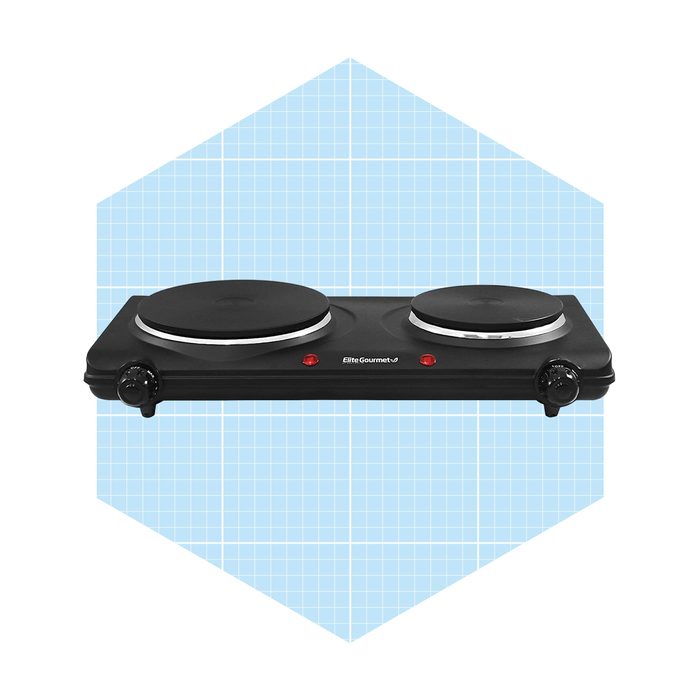 A black double hot plate sits on a light blue hexagonal background, featuring two heating elements and control knobs for adjusting temperature settings.