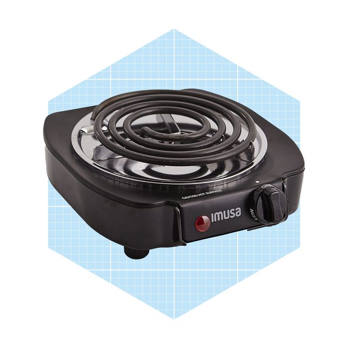A portable electric burner sits on a light blue grid background, featuring a circular heating element and a control knob for adjusting temperature.
