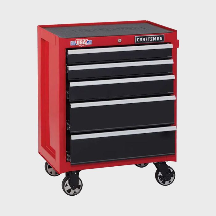 A red tool chest with four black drawers is positioned on wheels, designed for organizing tools in a workshop or garage setting.