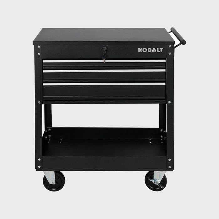 A black tool chest with four drawers and a lower shelf stands on wheels, designed for storage and organization in a workshop or garage setting.