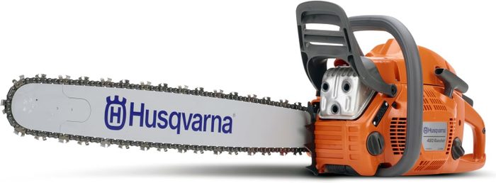 A chainsaw rests on a flat surface, ready for use, showcasing its orange body and metal blade with the 