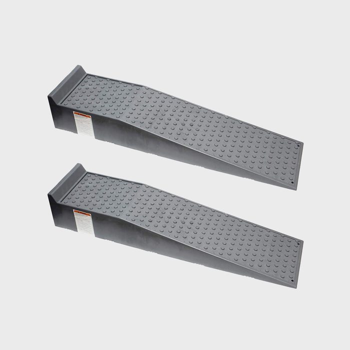 Two grey plastic ramps are positioned parallel, designed for vehicle elevation, with textured surfaces for traction against a plain background.