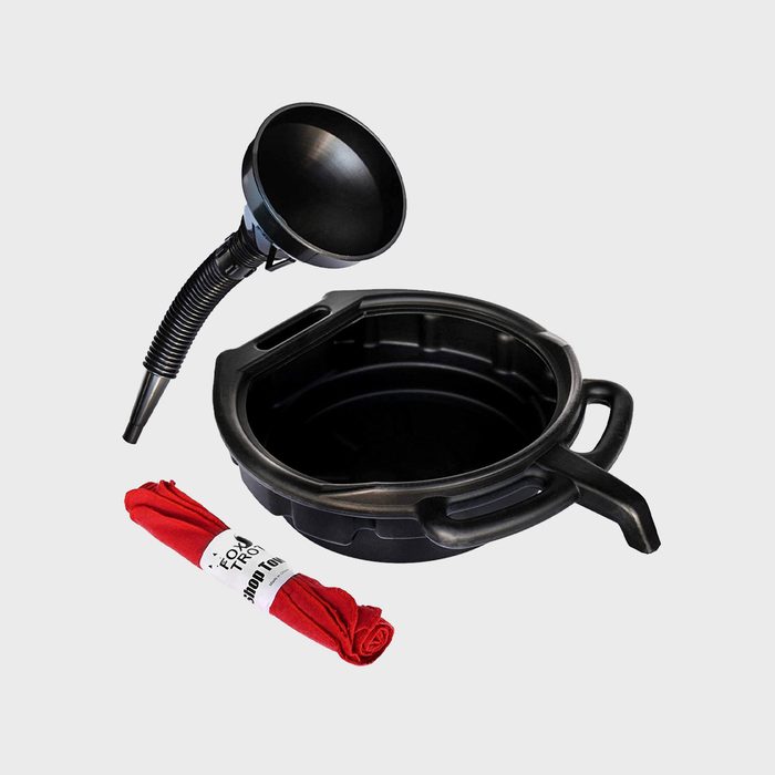 A black funnel is placed above a shallow container with two handles, accompanied by a rolled red cloth, set against a plain background.