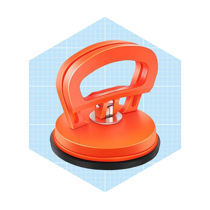 An orange suction cup with a handle lifts objects, set against a light blue grid background, suggesting a tool for moving heavy materials.