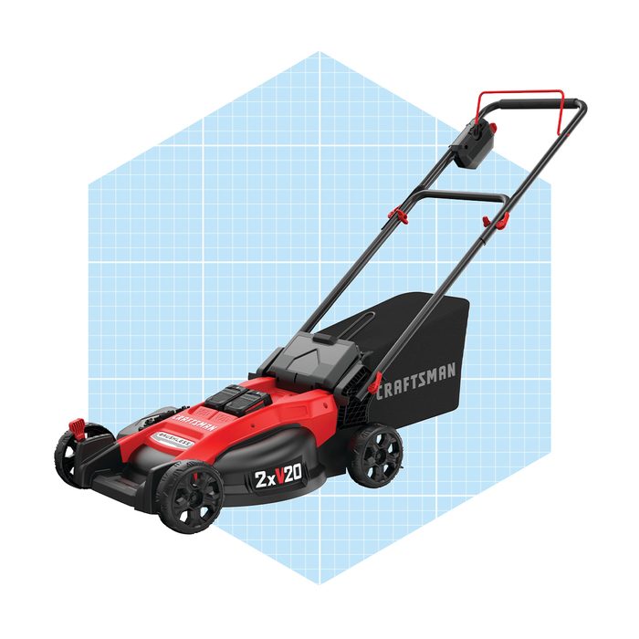 A red and black electric lawn mower rests on a light blue grid background, featuring a grass collection bag and adjustable handle.