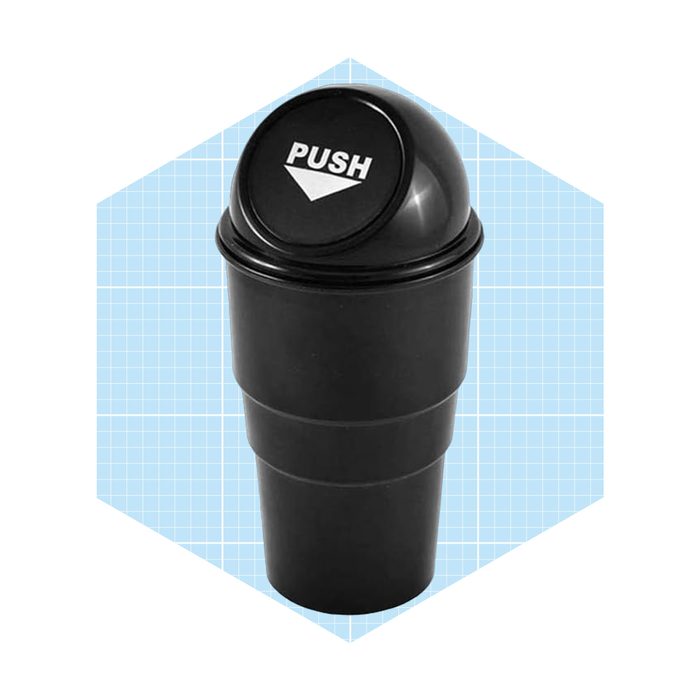 A black, two-part cylindrical container with a push-top lid sits against a light blue graph-patterned background, suggesting it