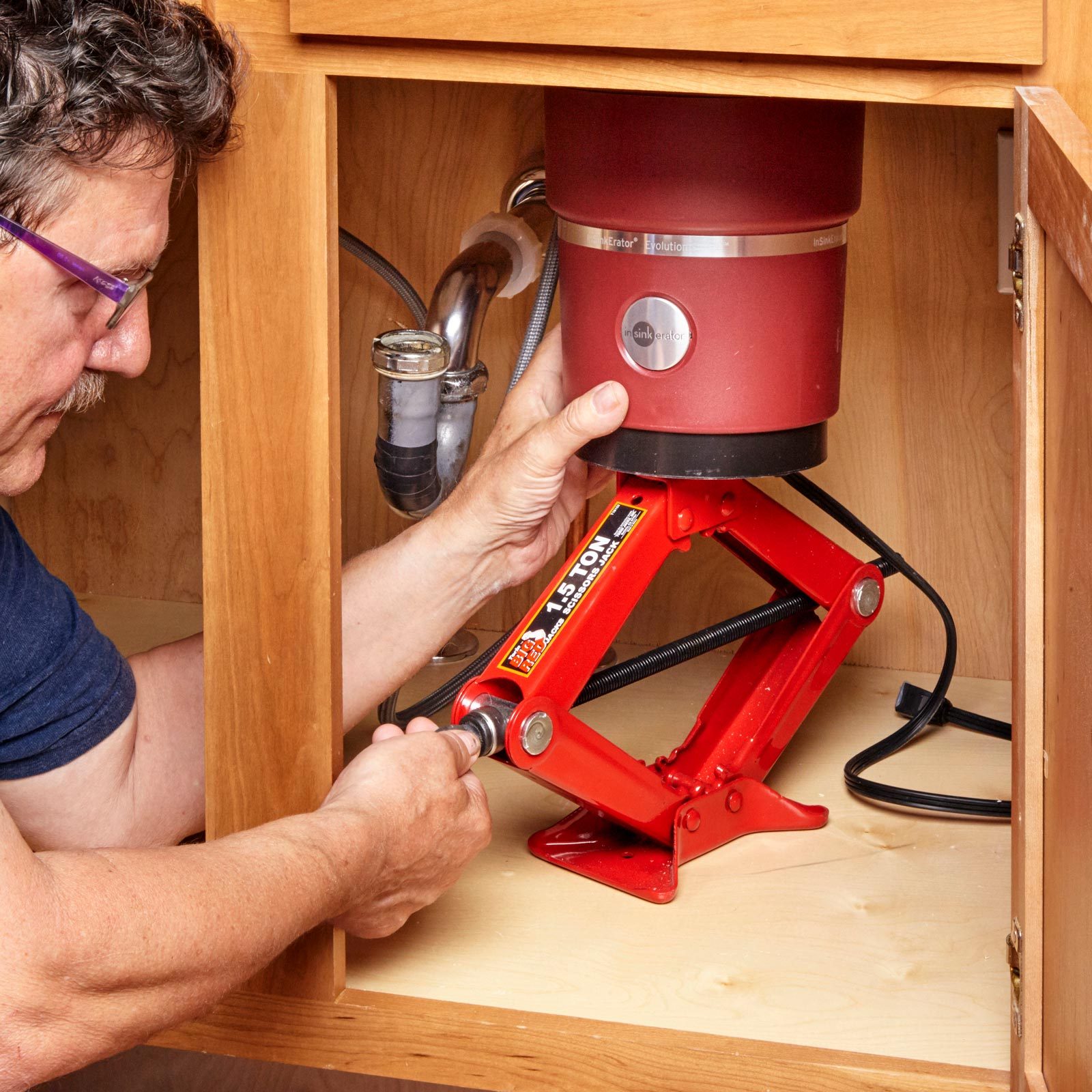 man repairing a garbage disposal under a sink