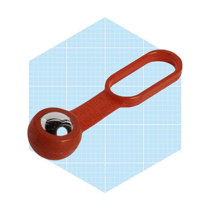 A red plastic object with a spherical end and a loop is displayed, against a light blue grid background, suggesting it is a tool or fastener.
