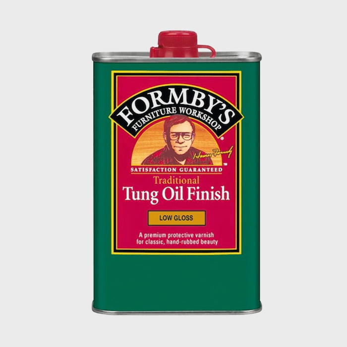 A green metal can contains traditional tung oil finish, labeled with product details and an image of a man, suggesting its use for furniture refinishing.