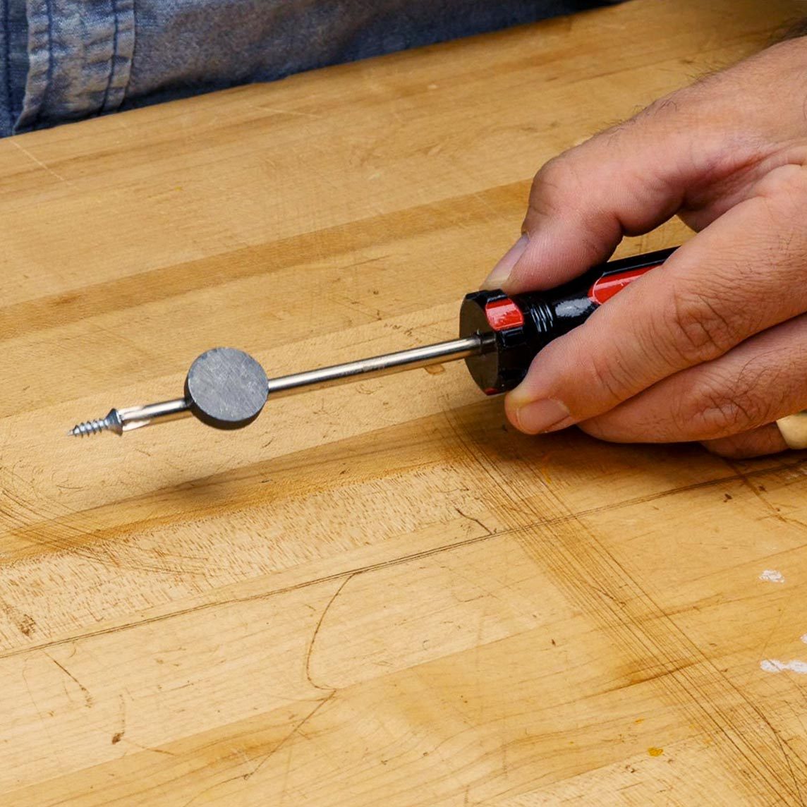 hand holding a screwdriver with a small round magnet at the tip