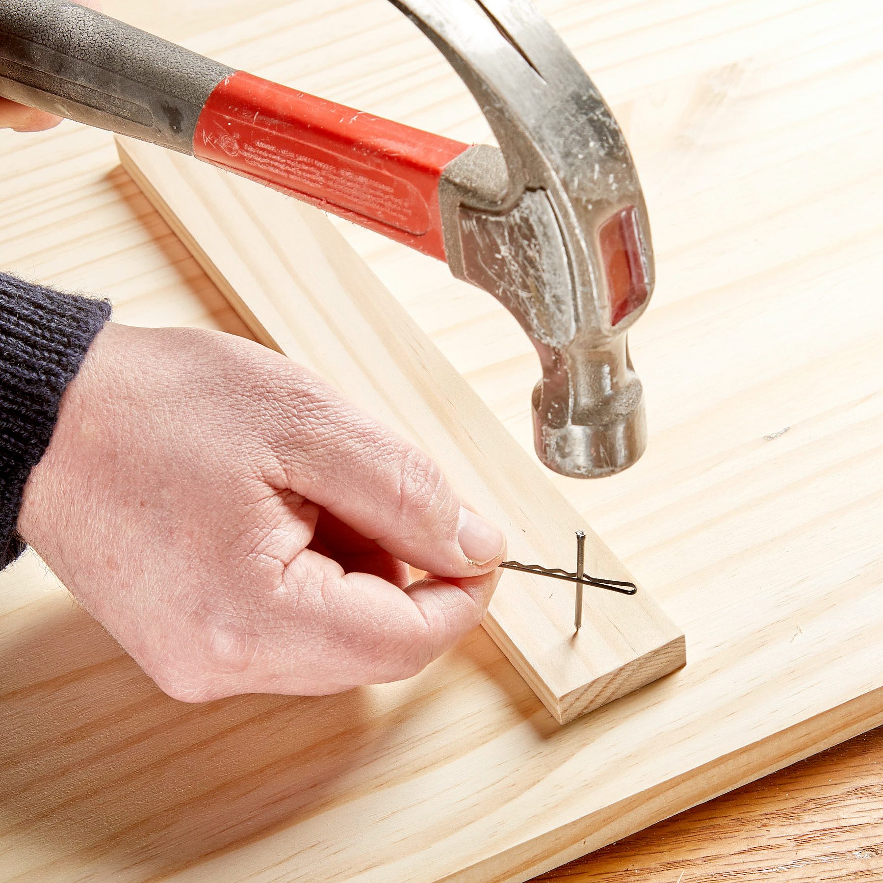 using a bobby pin to hold a nail to safely hammer into a piece of wood