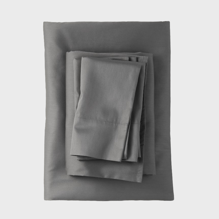 A stack of gray bed linens is neatly arranged, featuring a fitted sheet, flat sheet, and pillowcases, positioned against a clean, white background.