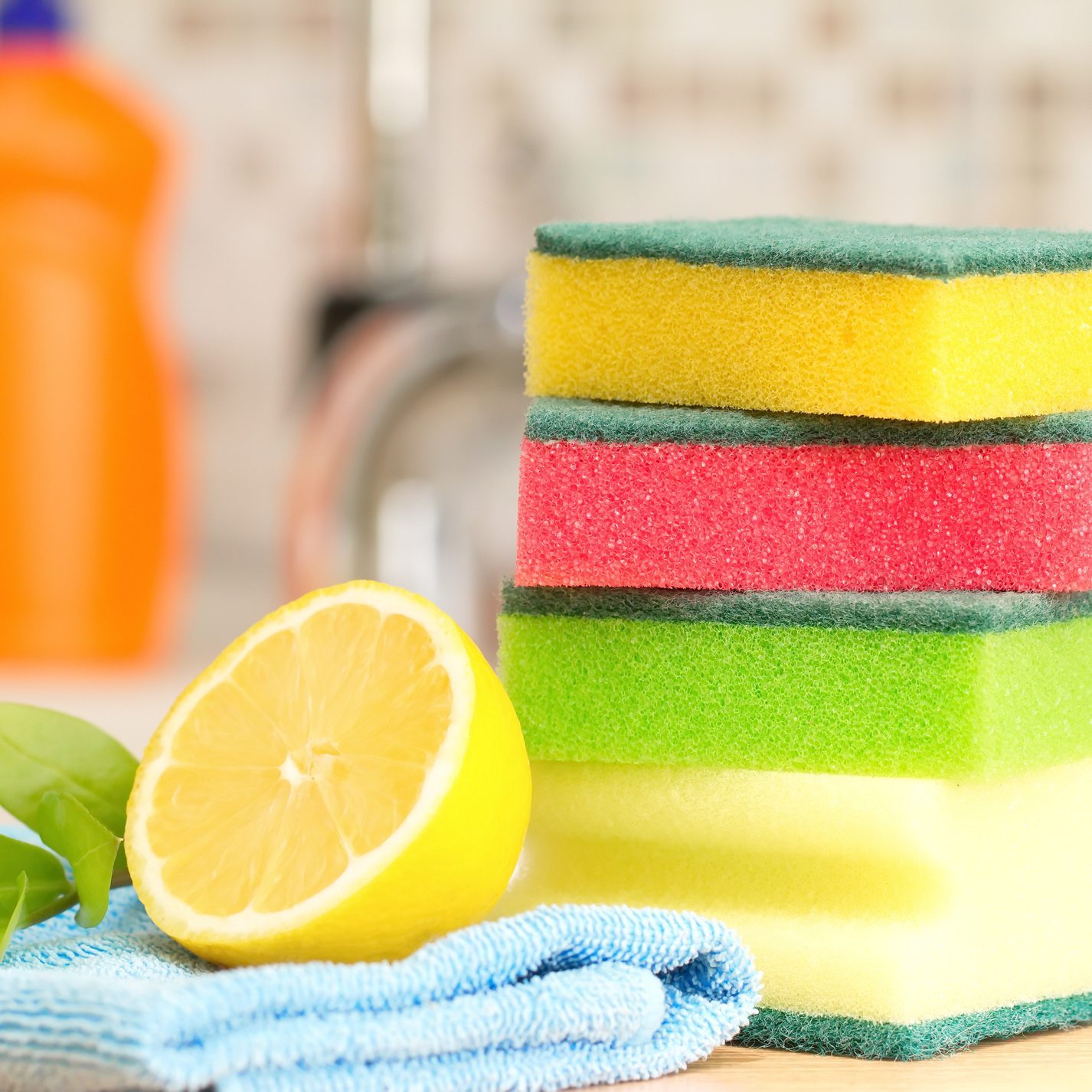 stack of colorful sponges with a sliced lemon in a kitchen for cleaning