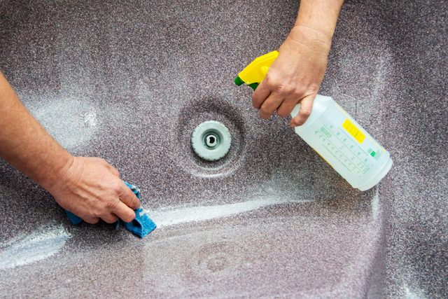 cleaning the hot tub with spray cleaner and a rag