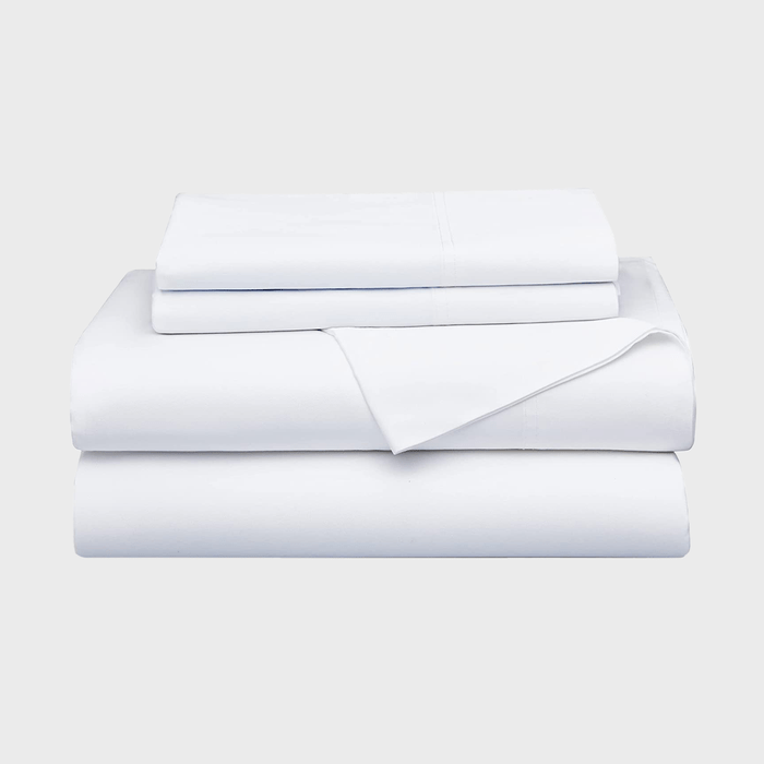 A neatly stacked set of white bed linens rests on a plain background, indicating a clean and organized space.