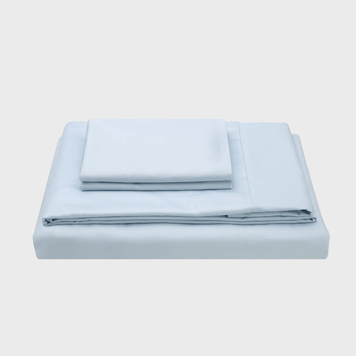 A neatly folded set of pale blue bed sheets and pillowcases rests on a light background, ready for use in a bedroom setting.