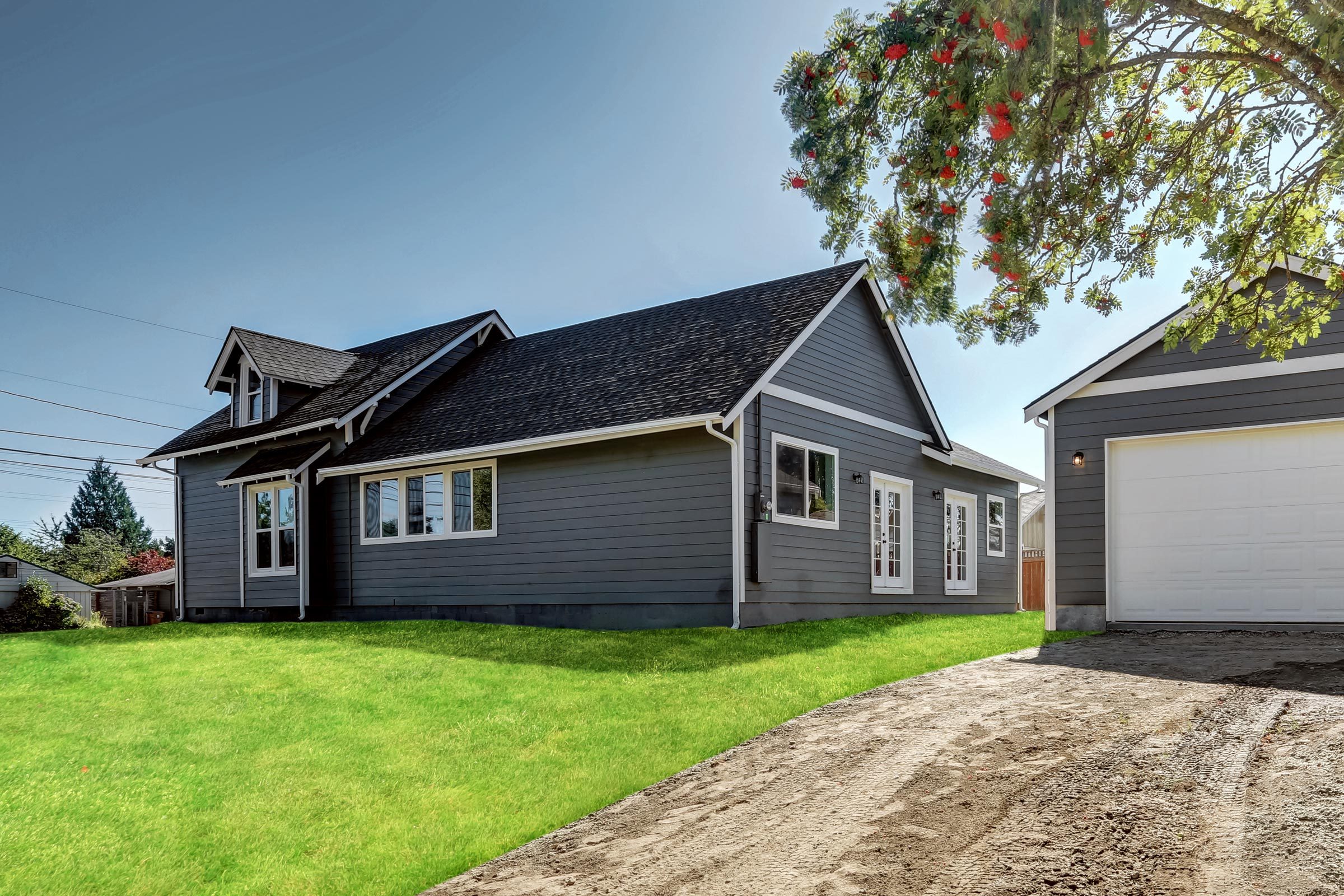 Backyard view of dark grey siding house with detached garage